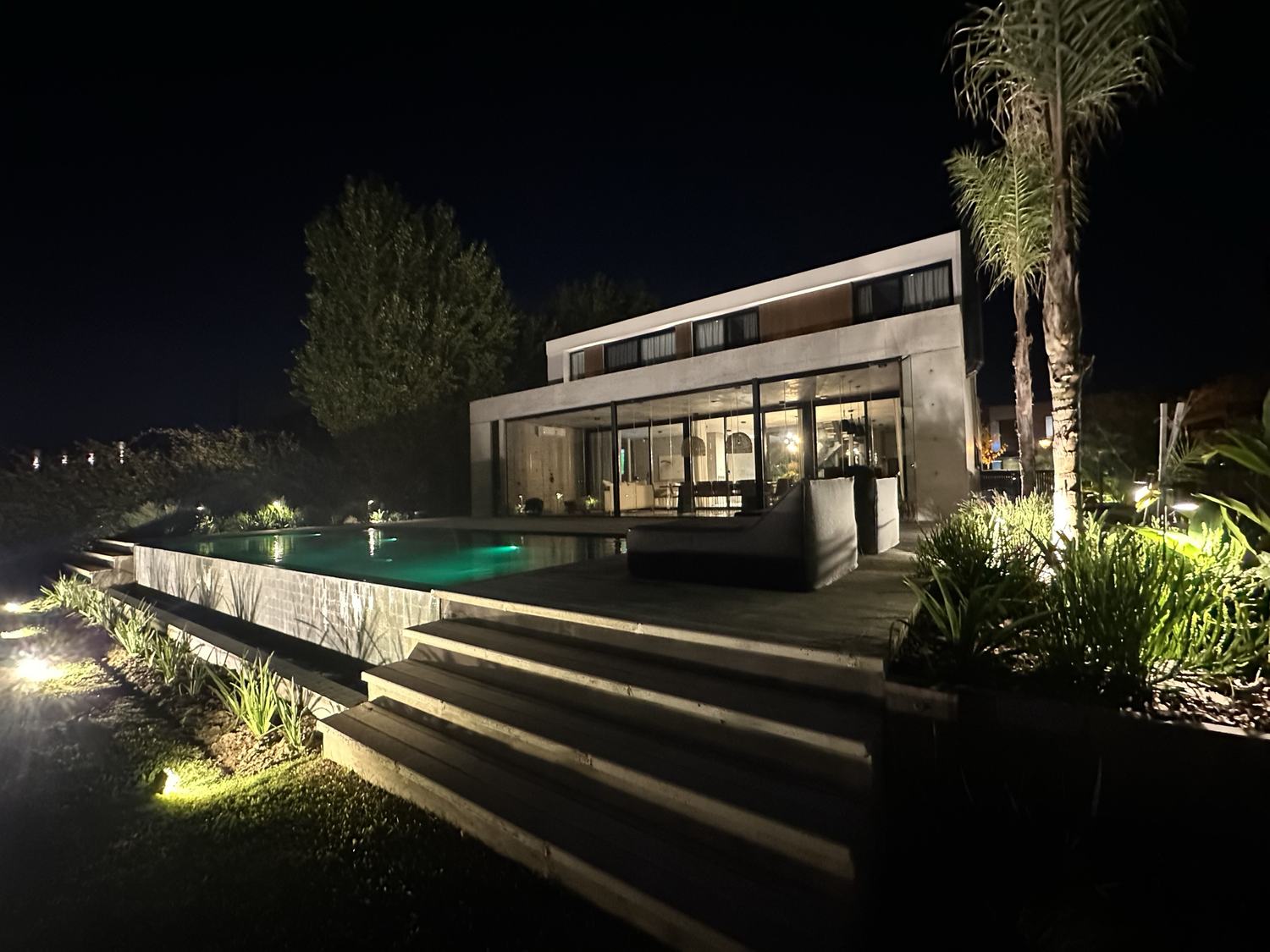 Vivienda con pileta y fachada iluminadas de noche